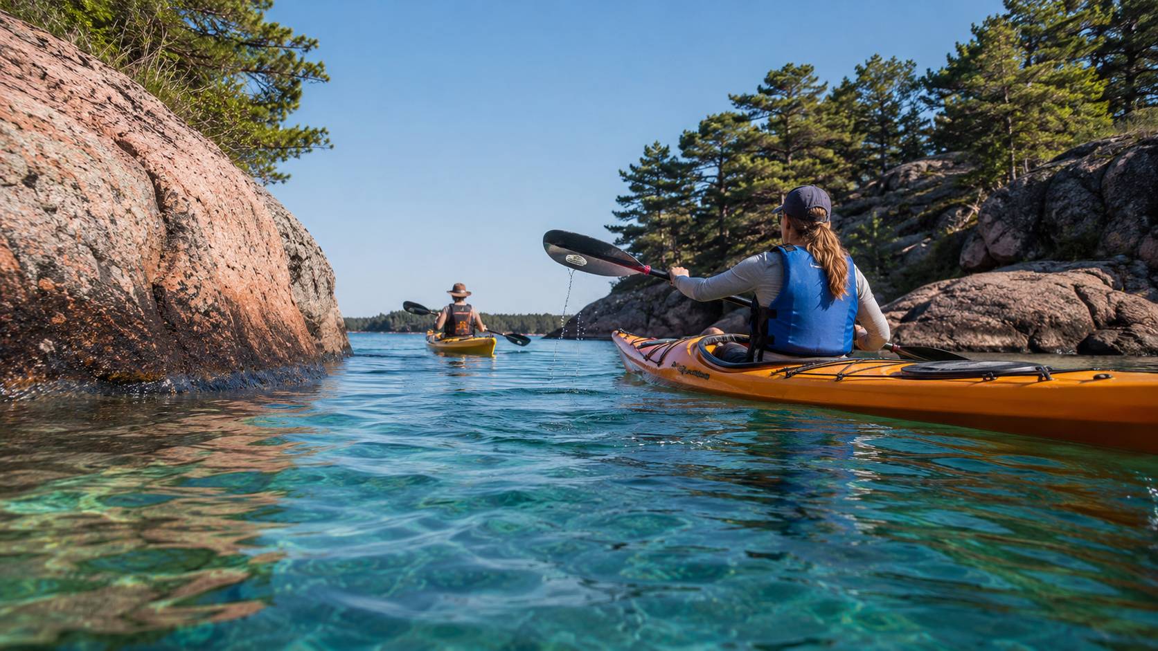 Kayakers paddling through a narrow channel between pine islands