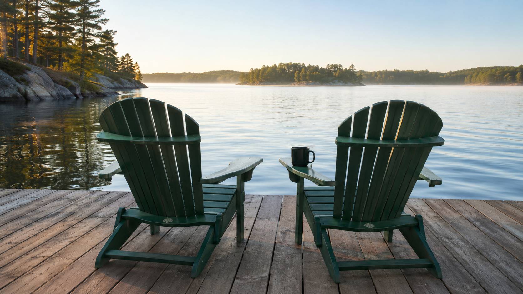 Two Muskoka chairs on a cedar dock facing calm water